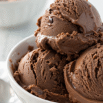 Scoops of creamy vegan chocolate ice cream in a white ceramic bowl.