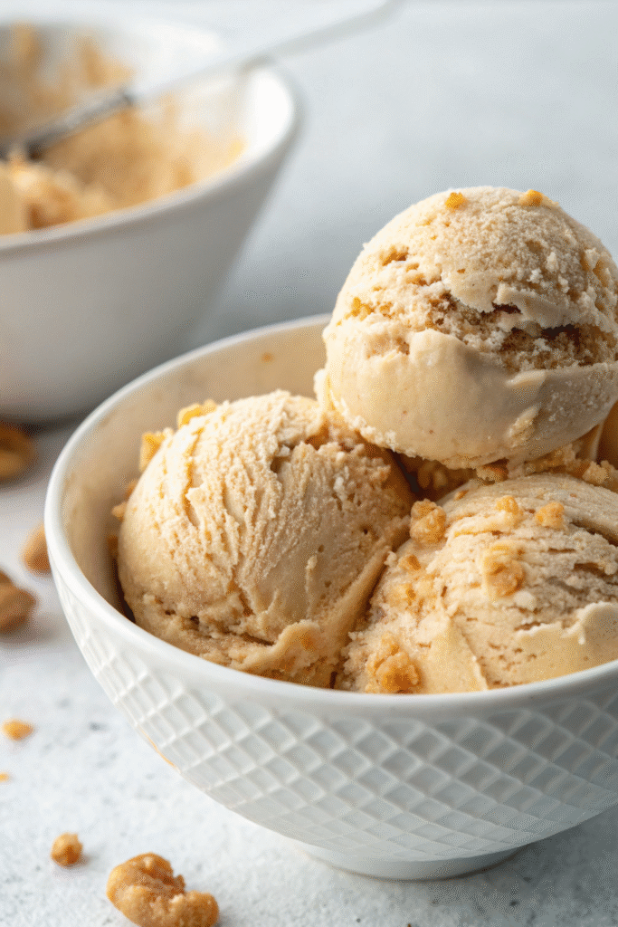 Vegan peanut butter ice cream in a textured white bowl topped with cookie crumbles.