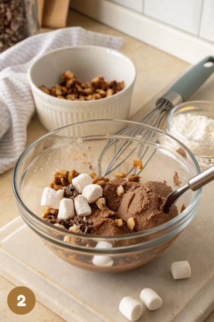 Bowl with chocolate ice cream, marshmallows, and nuts being mixed