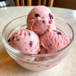 A bowl of creamy vegan berry ice cream with dark berry pieces.
