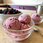 Scoops of vegan blackberry ice cream in a glass bowl.