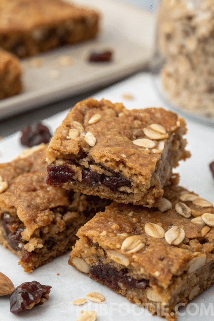 Homemade fruit granola bars with chopped dates, oats, and nuts stacked on parchment paper, healthy and chewy snack.