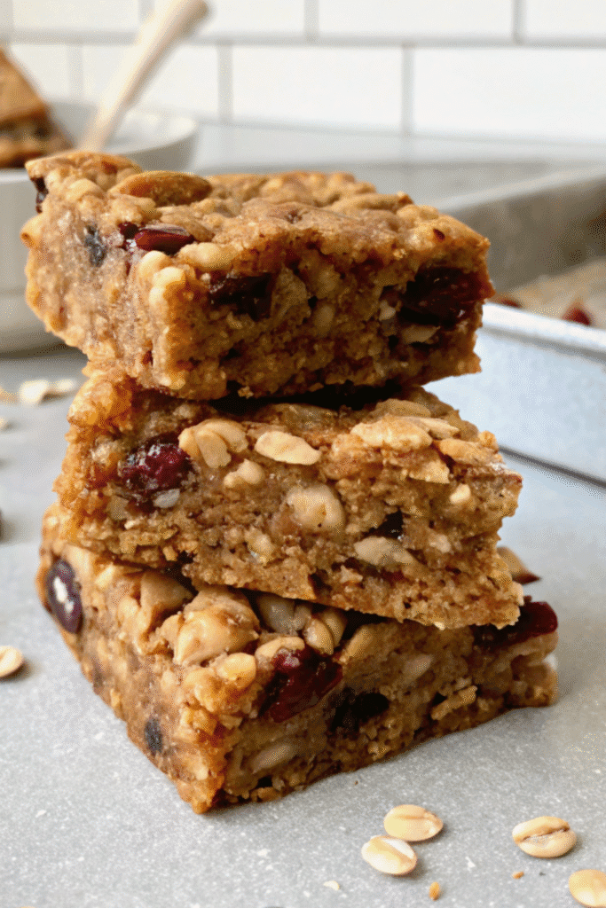 Close-up of stacked homemade fruit granola bars with oats, nuts, and cranberries.