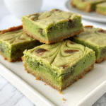 Close-up of green cheesecake bars stacked on a white plate