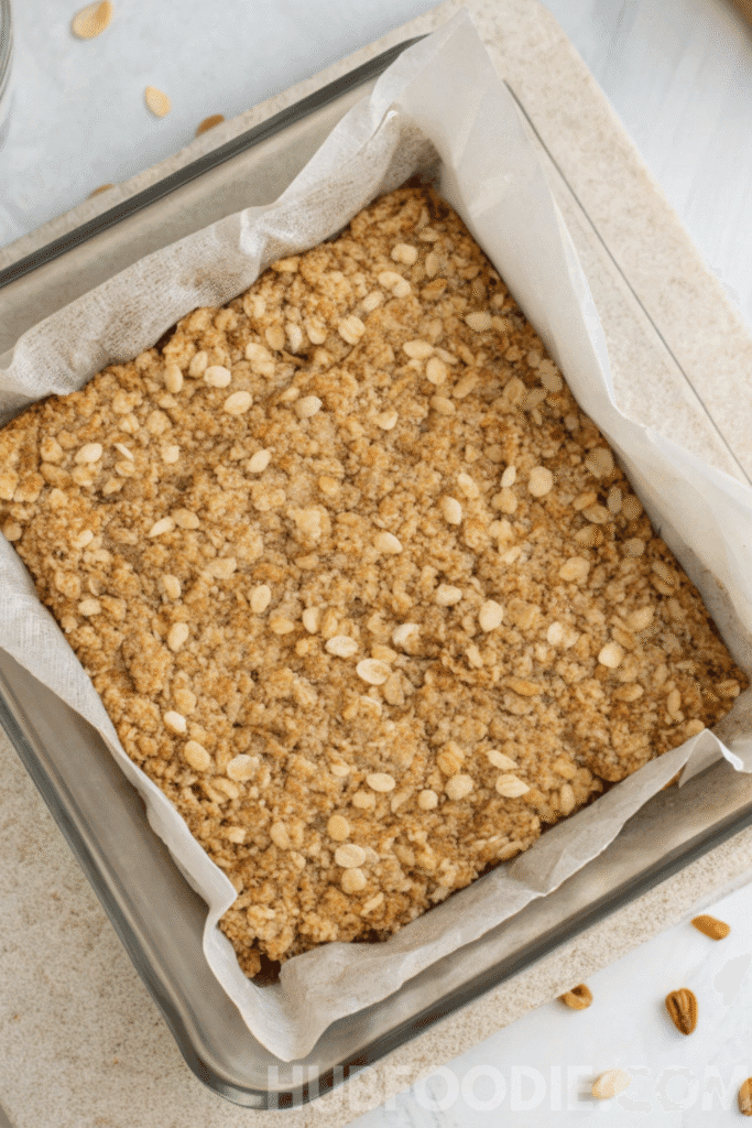 Step 4 of homemade gluten free granola bars recipe – oat mixture pressed firmly into a parchment-lined baking pan, ready to chill or bake.