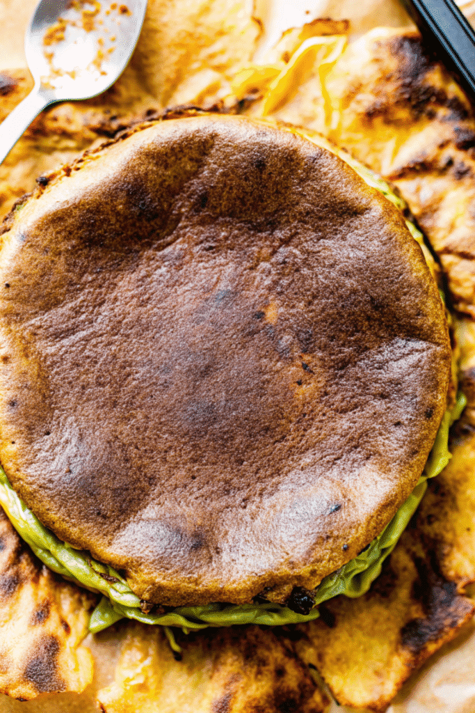 freshly baked matcha cheesecake with parchment paper removed, showing smooth browned top and vibrant green edges