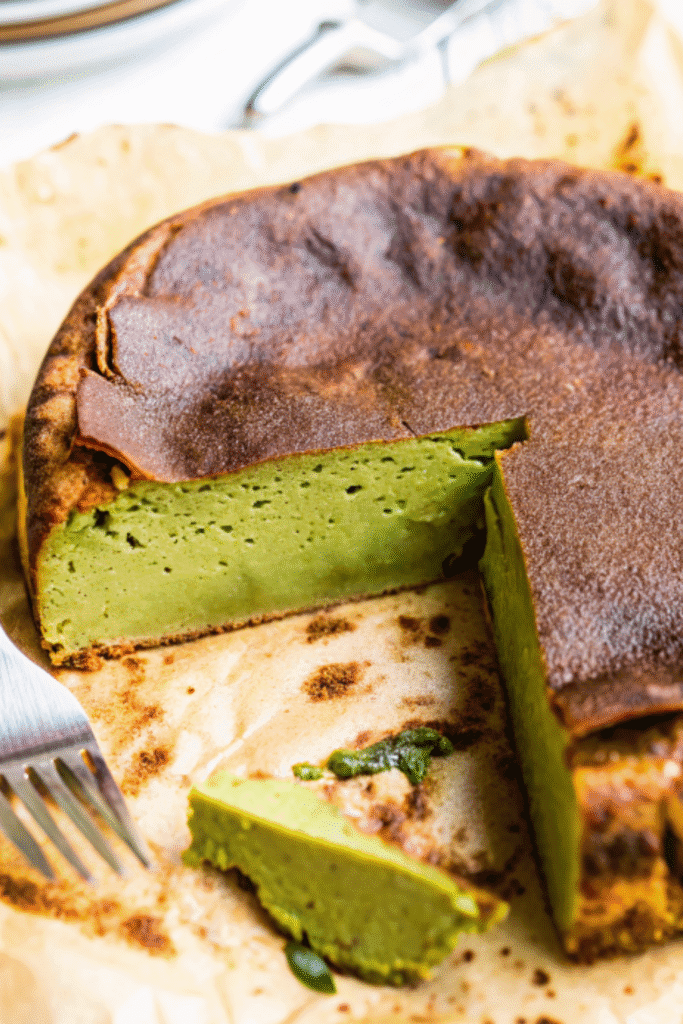 Slice of baked matcha cheesecake with golden-brown crust and creamy green interior