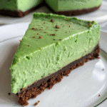 Close-up slice of no-bake green velvet cheesecake with chocolate crust on a white plate