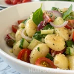 Gnocchi pasta salad with cherry tomatoes, cucumber, and herbs.