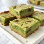 Green cheesecake Recipe 22 Green cheesecake bars with a swirled top, served on a white plate.