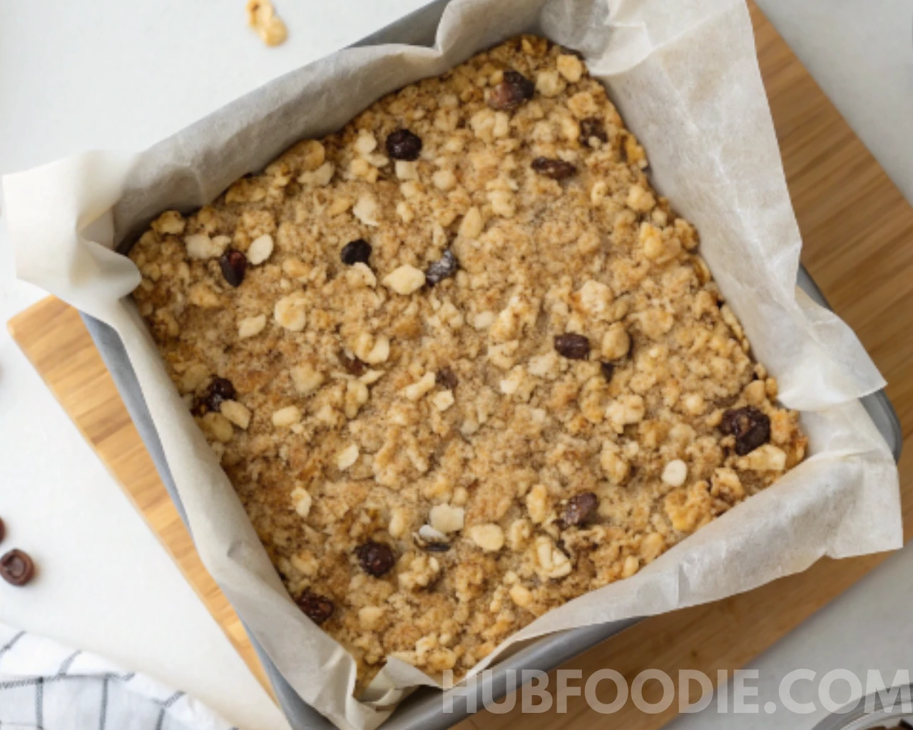 Nut Free Granola Bars Recipe 17 Pressed granola bar mixture in a parchment-lined square pan, ready to be baked or chilled