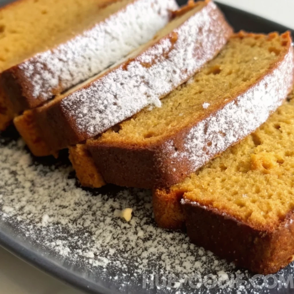 lemon squash bread recipe 32 Close-up of squash bread slices dusted with powdered sugar on a black plate.